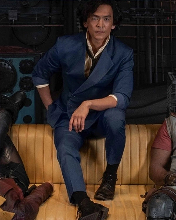 Man in a blue suit sitting on a couch with a dark background