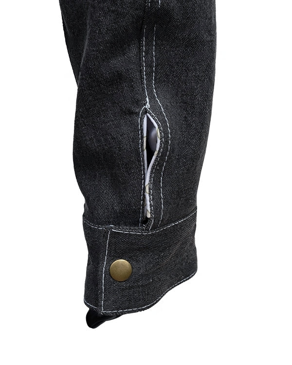 Close-up of a black denim knee patch with a button on a white background
