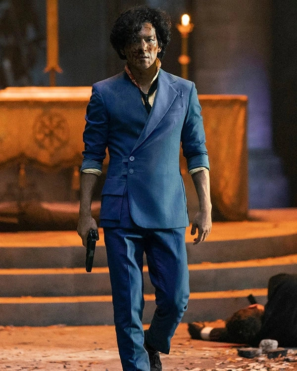 Person in a blue suit holding a gun, standing on steps with a dark background
