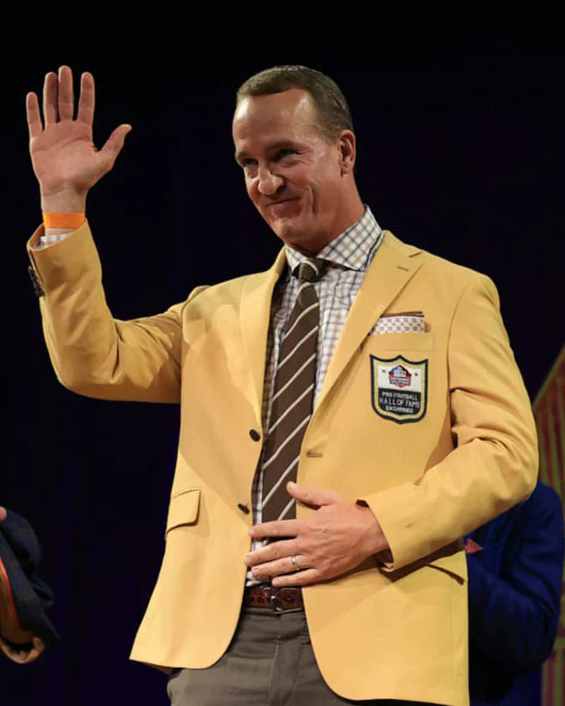 Man wearing a yellow blazer with a sports league emblem, waving at an event.