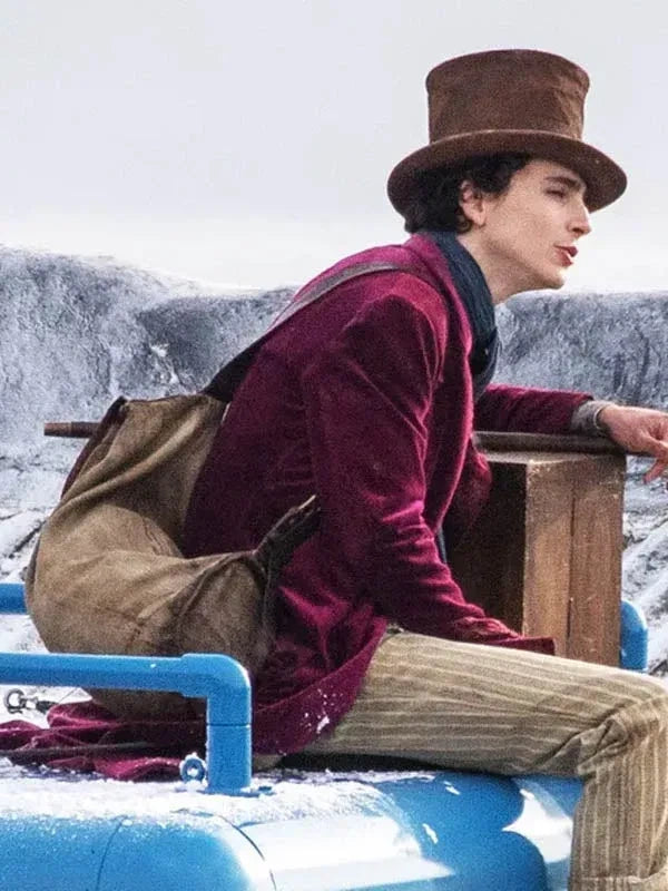Person in vintage attire with a top hat and backpack sitting on a snowy landscape.