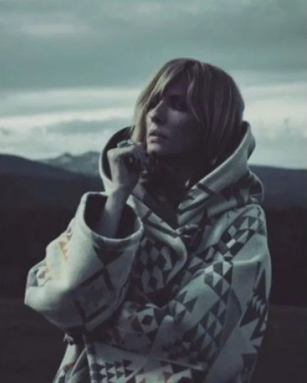 Person wearing a patterned coat with a mountainous landscape in the background