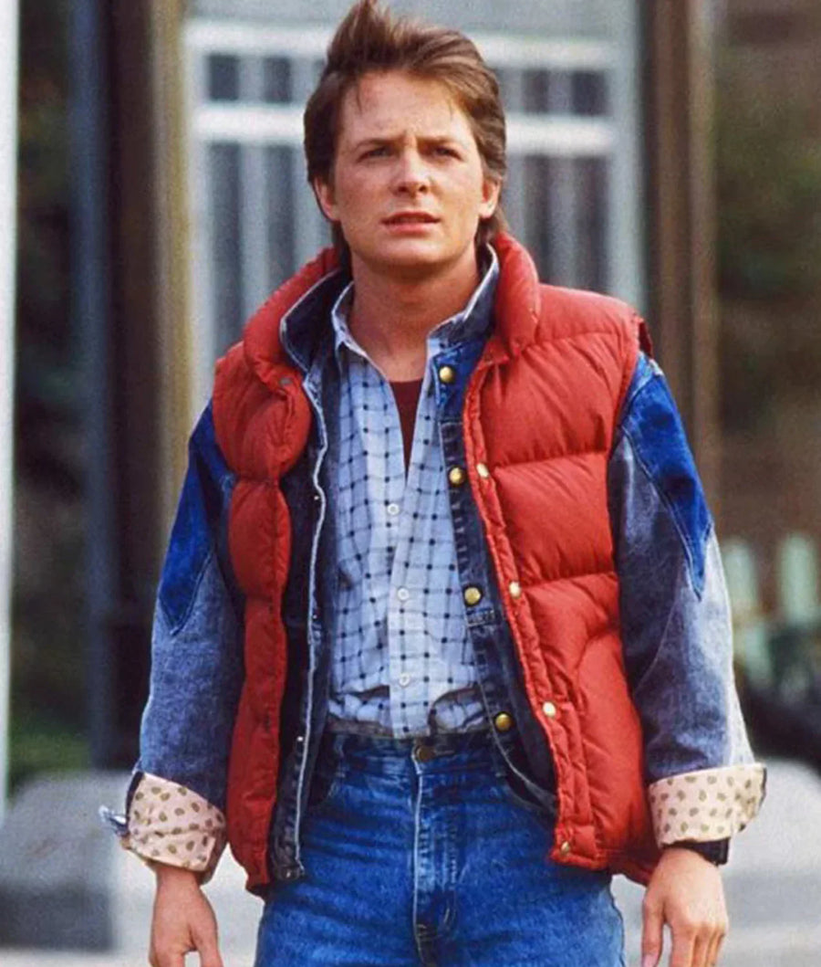 Person wearing a red and blue puffer jacket with a plaid shirt and jeans outdoors.